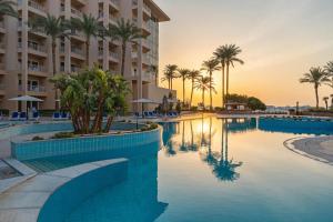 a swimming pool with palm trees and a building at Hurghada Marriott Beach Resort in Hurghada