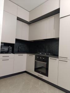 a white kitchen with white cabinets and an oven at Новобуд Автовокзал Стрийська Арена King Cross in Lviv +13 photos