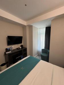 a hotel room with a bed and a flat screen tv at Mit Hotel Tbilisi in Tbilisi City