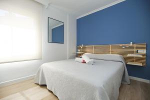 - une chambre avec un lit blanc et un mur bleu dans l'établissement Apartment TOUS 2 - Only Families, à Salou