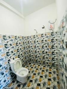 a bathroom with a toilet and a tiled wall at Sasaa Guest House in Mirissa