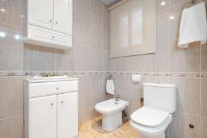 a white bathroom with a toilet and a sink at Apartamento VIKING in La Pineda +11 photos