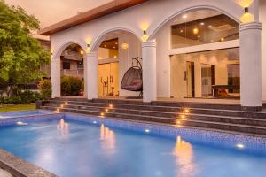 a swimming pool in front of a house at Happy Home by Leo Homes - 2BHK Flat in Candolim in Candolim