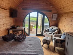 a room with a bed and two chairs and a table at Stargaze at OLJU Lodges in Stithians