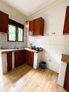 una cocina vacía con armarios de madera y fregadero en The soft stay, en Namugongo 6 fotos más