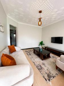 sala de estar con 2 sofás blancos y TV de pantalla plana en The soft stay, en Namugongo