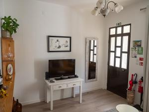 a living room with a tv on a white table at Casa do João e da Teresa in Ribeira Brava