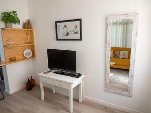 a living room with a tv on a table and a mirror at Traditional Madeira House Garden, Terrace & BBQ in Ribeira Brava