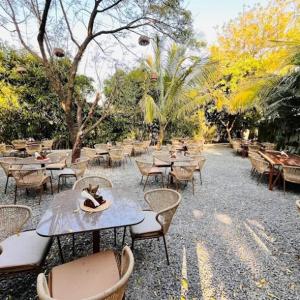 Un patio al aire libre con mesas, sillas y árboles. en Serene Fields Retreat, en Kanāria