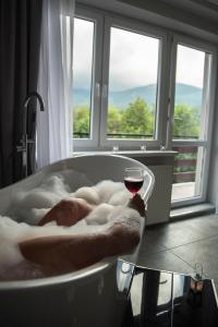 een persoon die in een badkuip ligt met een glas wijn bij FMA ski & bike in Szklarska Poręba