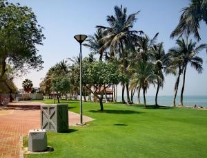 a park with palm trees and a street light and the ocean at High Residence - Spacious & Lux Apt in Muscat