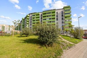 a green and white apartment building in a park at 1-bedroom apartment with balcony, Rustaveliho - Rača in Bratislava