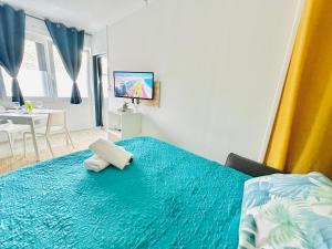 a bedroom with a bed with blue sheets and a television at Ipanema, Train Lens - Paris trajet d'environ 1 heure 10 minutes in Lens
