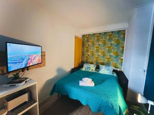 a bedroom with a blue bed with a flat screen tv at Ipanema, Train Lens - Paris trajet d'environ 1 heure 10 minutes in Lens