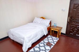 a small bedroom with a bed and a table at Richard's Road Homestay in Boma la Ngombe