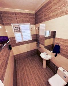 Un baño con lavabo, inodoro y espejo. en Embassy Loagde Inn, en Mussoorie