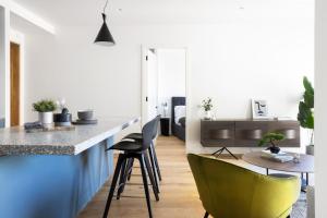 a kitchen with a counter and two green chairs at Native Verso in London +9 photos