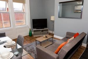 a living room with a couch and a tv at Bewick Apartments in Newcastle upon Tyne