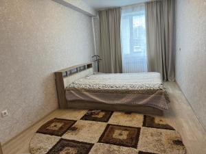 Schlafzimmer mit einem Bett, einem Fenster und einem Teppich in der Unterkunft 3х комнатная квартира in Öskemen + 3 Fotos