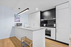 une cuisine avec des comptoirs blancs et des armoires noires dans l'établissement Stylish Dickson 1BR Perfect for Business and Leisure, à Downer 21 autres photos