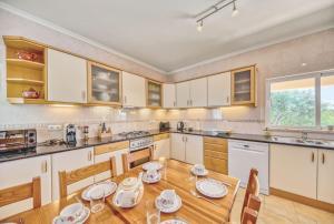a kitchen with white cabinets and a wooden table at Casa Vista Cumeada in Canhestros