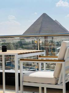 a balcony with two chairs and the pyramid in the background at Giza Capital Hotel in Cairo