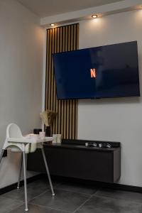 a tv on a wall with a table and a chair at The Golden Wolf - Wellnes & Spa Luxury Apartment - SELF CHECK IN - FREE PARKING in Vukovar