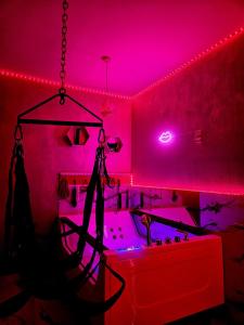 Una habitación con luces rosas y una persona parada en una bañera. en Secret love room, en Bucarest