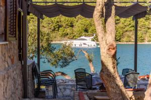 a table and chairs with a boat in the water at Villa Zora ZadarVillas - private island retreat in Sali