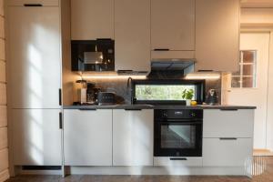a kitchen with white cabinets and a refrigerator at Levi Kätkänlinna 20A by Holiday in Lapland in Kittilä