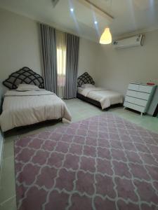 a bedroom with two beds and a rug on the floor at شقق الهجرة 101 in Al Madinah