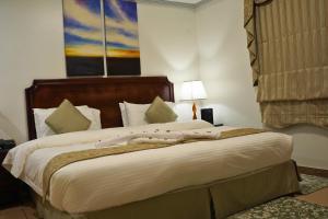 a bedroom with a large bed with white sheets at Sand Rose Hotel Apartments in Al Khobar