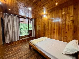 a bedroom with wooden walls and a bed with a window at ukiyo homes in Darjeeling