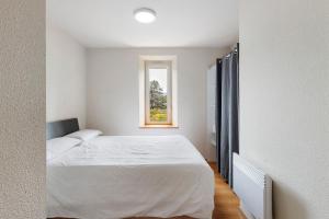 una camera da letto con un letto bianco e una finestra di Apto Buenas Vistas En Osseja a Osséja