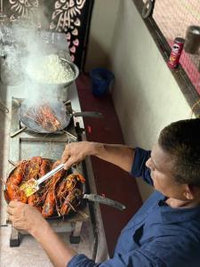 a man is cooking food on a grill at AbbA Marari Beach Villas & Homestay Mararikulam in Alleppey