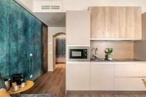 a kitchen with white cabinets and a green accent wall at Casa Abelia - Boutique Apartment in Venice