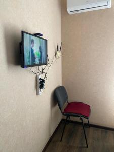 Habitación con silla y TV en la pared. en #8 Apartments, en Odessa