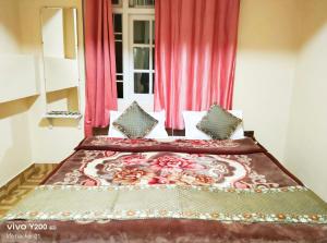 a bedroom with a large bed with red curtains at SnowCap Regency in Gangtok