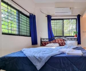 a bedroom with a blue bed and two windows at Your perfect high standart cosy Home near Arambol with 2BHK in Arambol