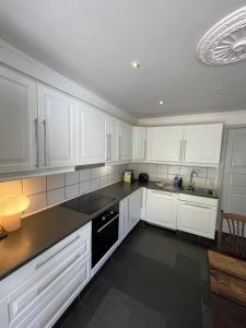 a kitchen with white cabinets and a black dishwasher at Spacious Private House in Amager in Copenhagen