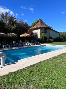 a swimming pool with chairs and umbrellas and a building at Sequoia cottage in Bersac-sur-Rivalier