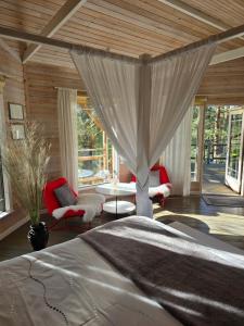 a bedroom with a large bed in a room with windows at Treehouse Čiekurs in Duķuri