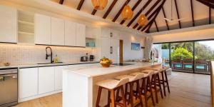 a kitchen with white cabinets and a bar with stools at Lagati Luxury Villa in Mahe
