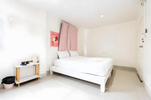 a white bedroom with a bed and a table at Nap BTS Soi 3 in Makkasan