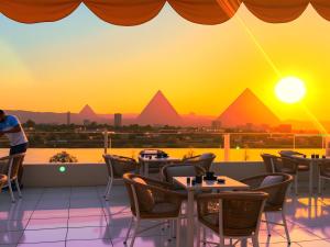 a view of the pyramids from a restaurant with tables and chairs at GOLDEN PYRAMiDS TEMPLE ViEW HOTEL all king rooms with jacuzzi & pyramids view in Cairo