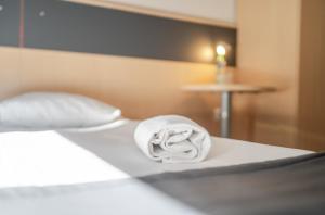 a white towel sitting on top of a bed at Aparthotel Skylight Katowice by BookingHost in Katowice