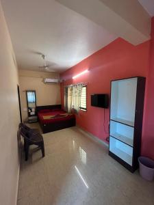 Habitación con pared roja, cama y TV. en Seeta residency, en Gokarna