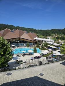 a resort with a pool with umbrellas and tables at Apartman O Terme Olimia in Ravne na Koroškem