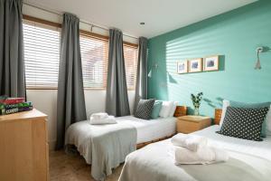 two beds in a room with blue walls and windows at The Garden House in Waterden +17 photos