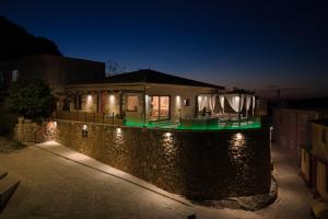 a house with a stone wall at night with lights at Villa Strada Castello in Zakynthos